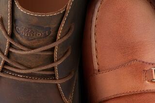 A close-up of two pairs of shoes: one brown lace-up with a comfort logo and another polished brown slip-on.